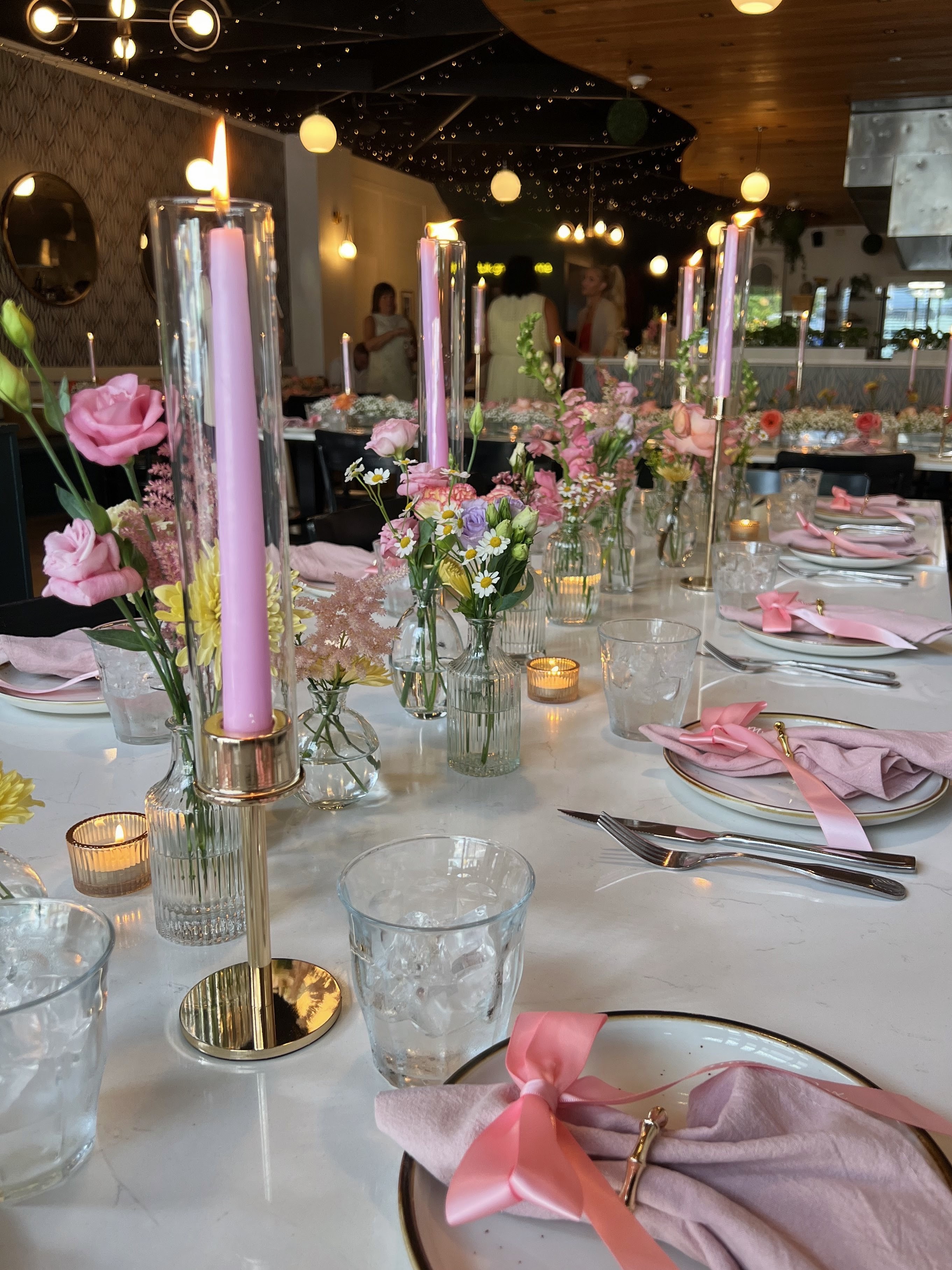 Private event table setup with pink candles and floral arrangements at Flavia’s